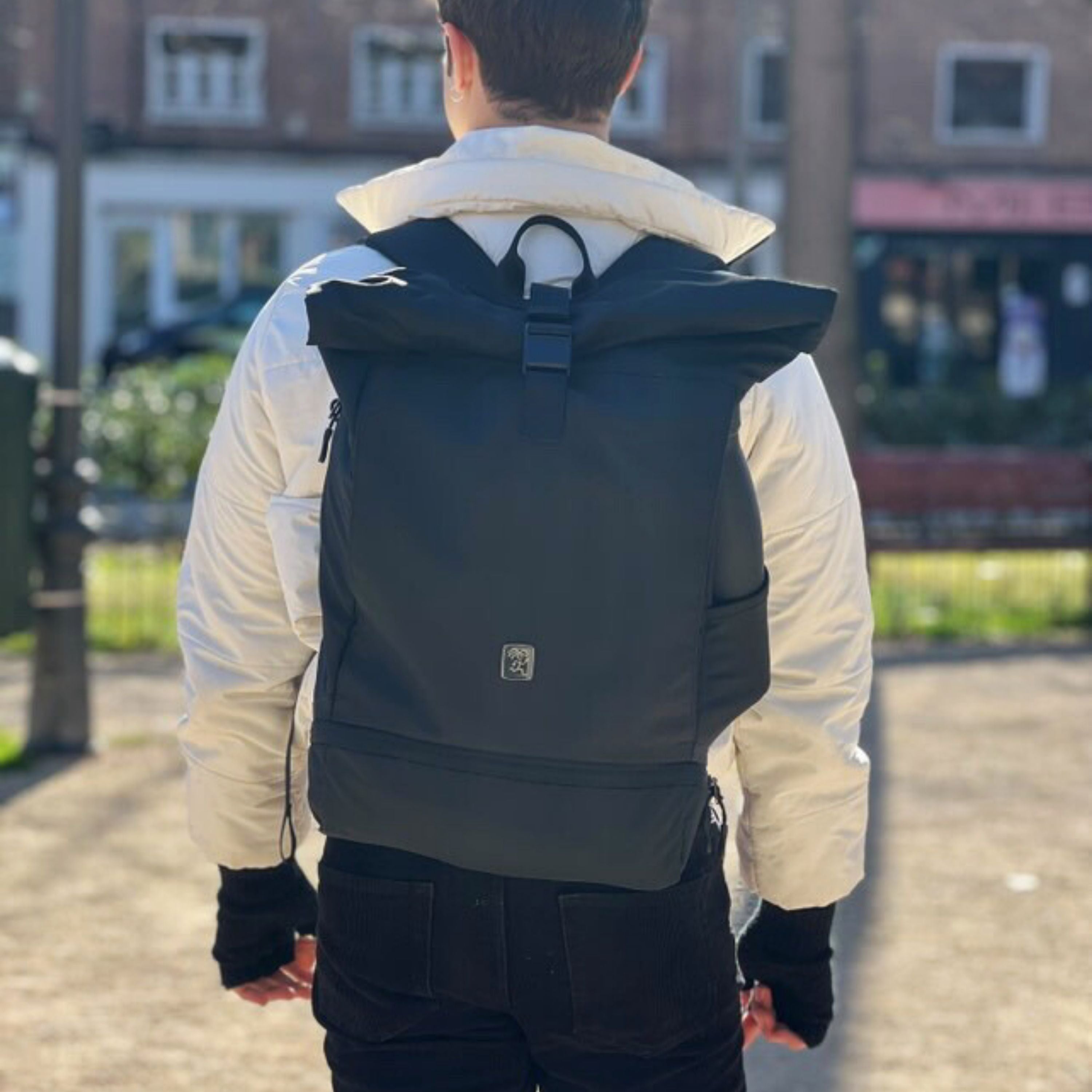 Mann traegt den FUCHS und REBELL EDDIE Rolltop Rucksack in schwarz.