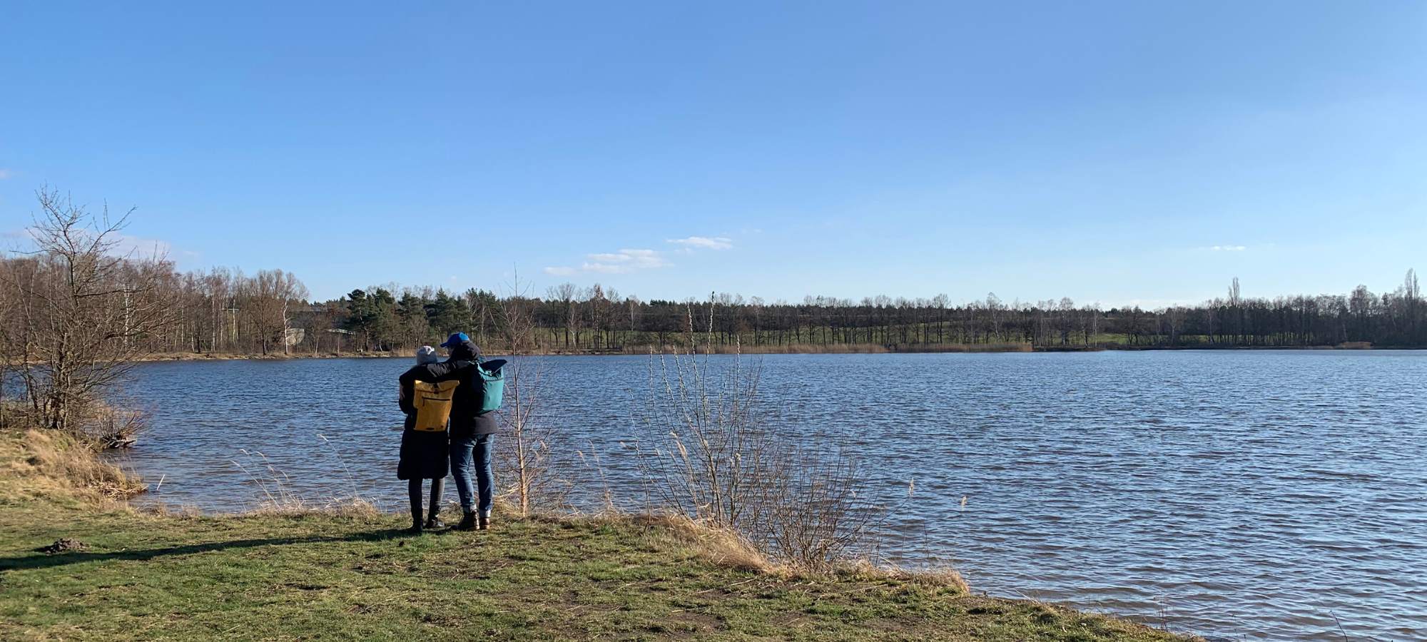 Paar am See mit den FUCHS und REBELL Rucksaecken PIET in gelb und petrolblau